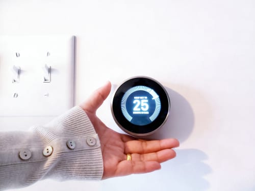 person adjusts Nest learning thermostat at home
