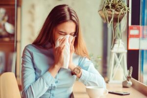 woman sneezes at home with allergies